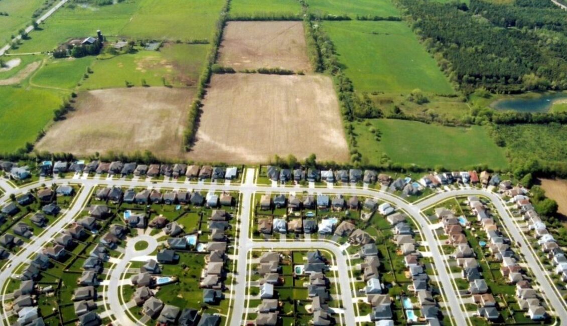 Photograph of a dense suburban neighbourhood abutting farmland