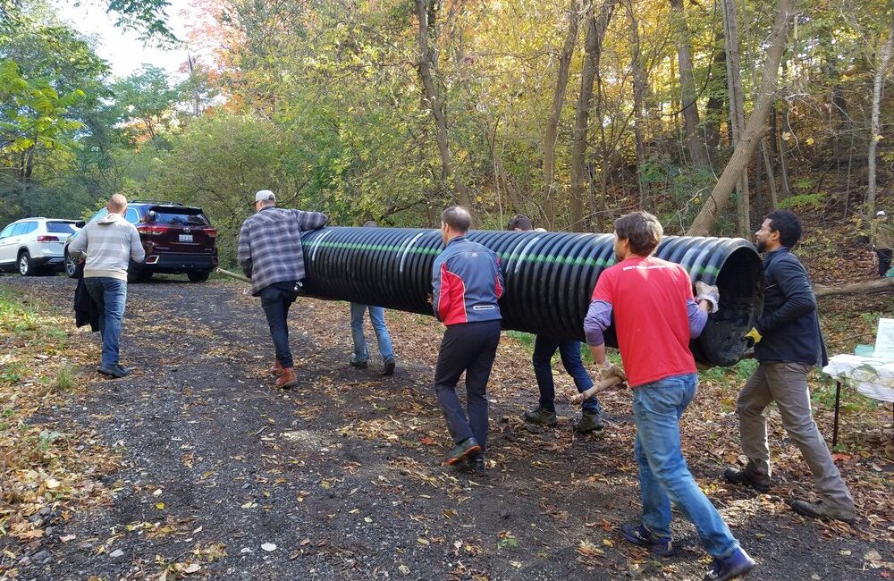 Several volunteers carrying a tube while cleaning up