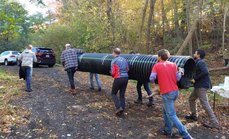 Several volunteers carrying a tube while cleaning up